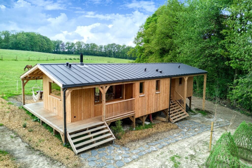 Cabane champêtre en bois au Domaine des Trois Tilleuls, entourée de verdure, idéale pour les séjours en groupe en pleine nature.