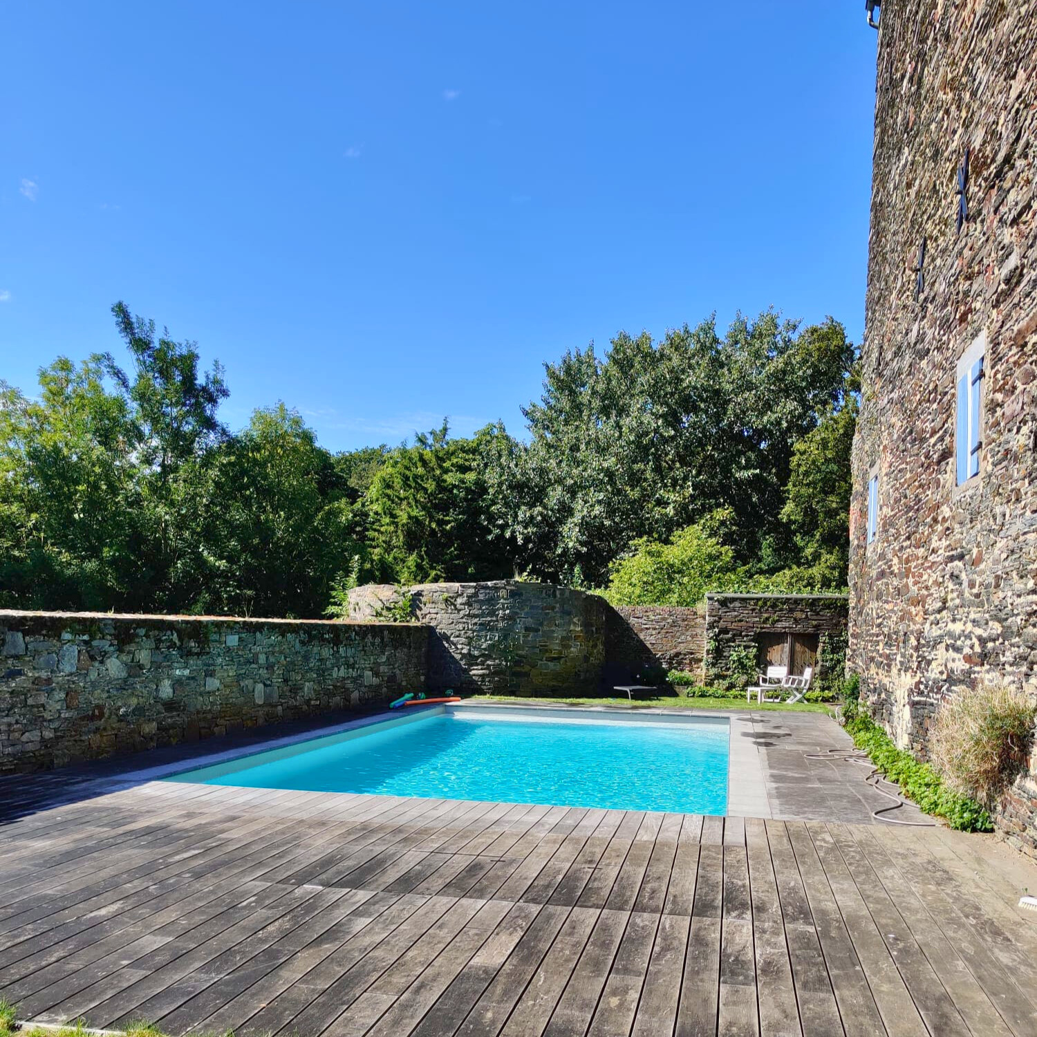 Piscine extérieure chauffée au Gîte du Château, entourée de murs en pierre du XIIIe siècle à Villers-la-Ville, offrant un cadre intime et historique en pleine nature.